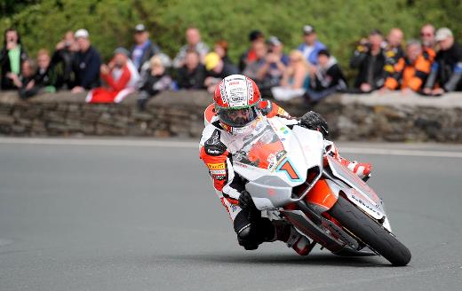 A man making a sharp turn on a motorcycle with a crowd cheering him on